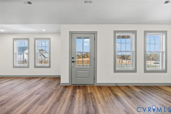 a view of an empty room with window and wooden floor