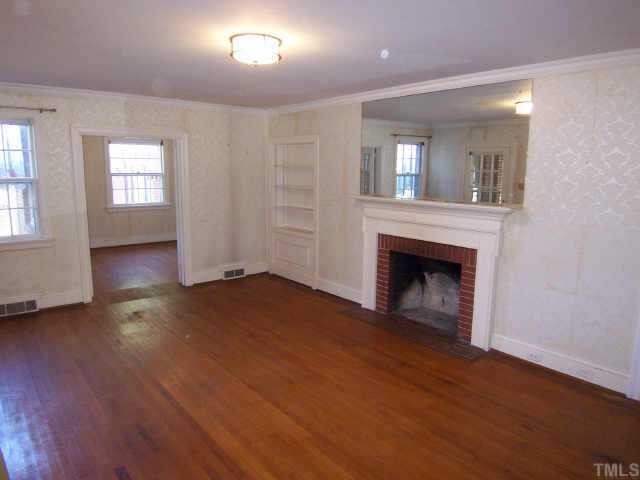 1402 Brooks Avenue Raleigh, NC 27608 - Photo 4 of 12 an empty room with wooden floor fireplace and windows