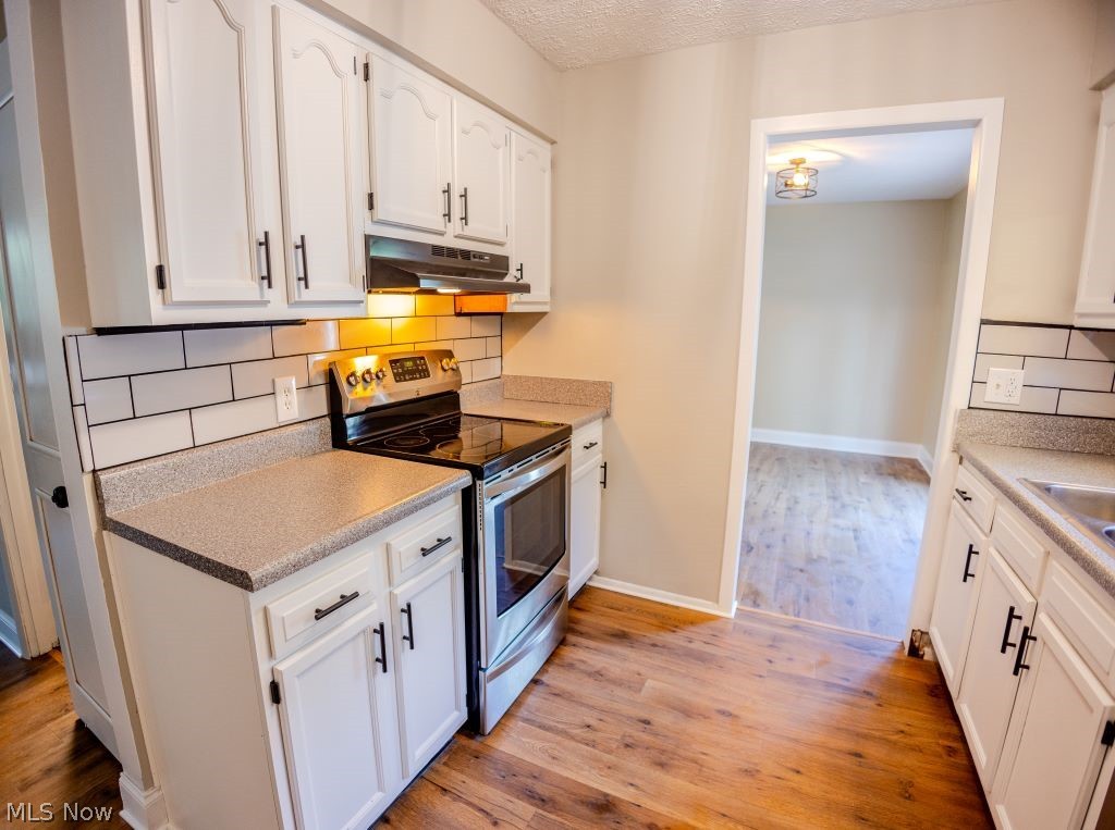 8828 Edgehill Road Mentor, OH 44060 - Photo 5 of 24 Kitchen featuring light hardwood / wood-style flooring, tasteful backsplash, stainless steel range with electric stovetop, and white cabinetry