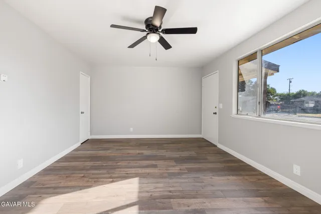 a view of empty room with wooden floor and fan