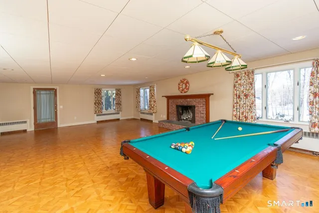 a room with pool table windows and a fireplace