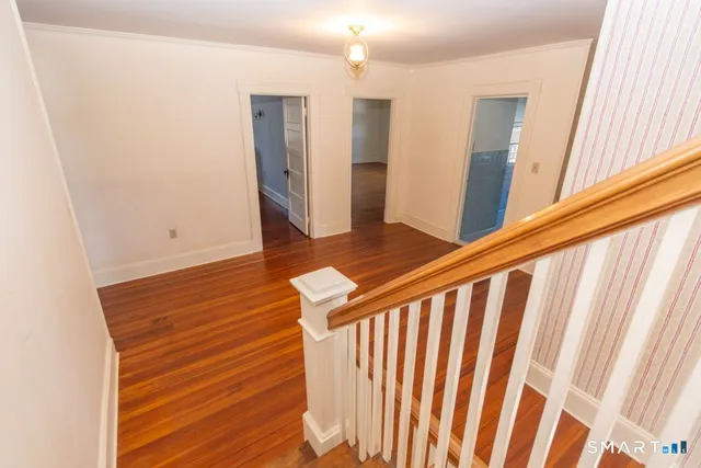 a view of a hallway with wooden floor and staircase