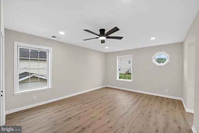 a view of an empty room with a window and wooden floor