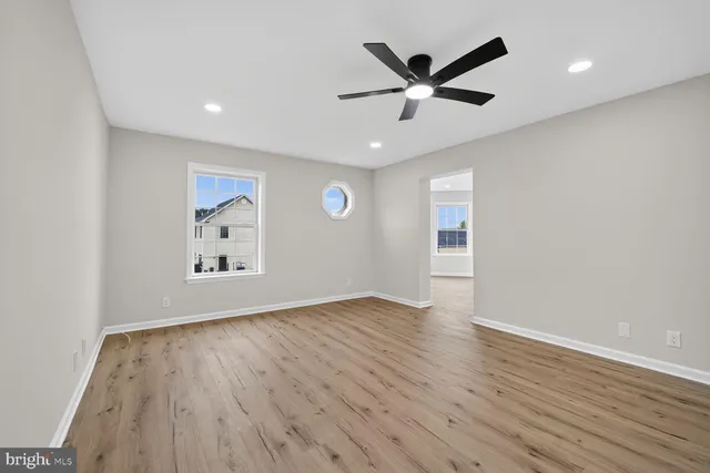an empty room with wooden floor and a ceiling fan