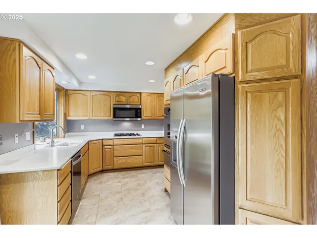 a kitchen with stainless steel appliances granite countertop a refrigerator a stove and a sink
