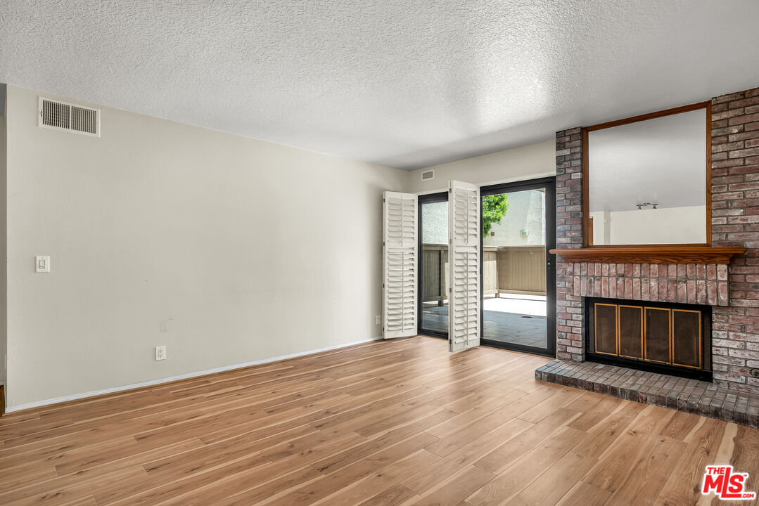 8512 Tuscany Avenue, Unit 207 Playa del Rey, CA 90293 - Photo 11 of 45 an empty room with wooden floor fireplace and windows