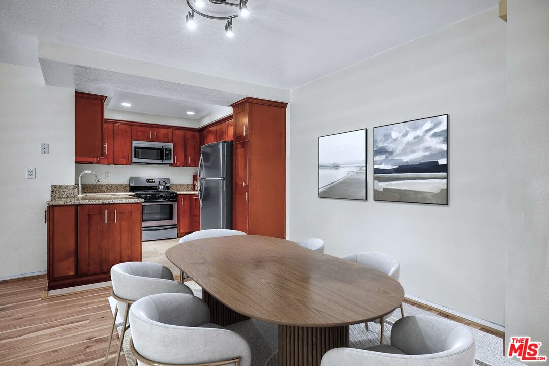 8512 Tuscany Avenue, Unit 207 Playa del Rey, CA 90293 - Photo 6 of 45 a kitchen with stainless steel appliances granite countertop a refrigerator a stove a sink and a dining table with wooden floor
