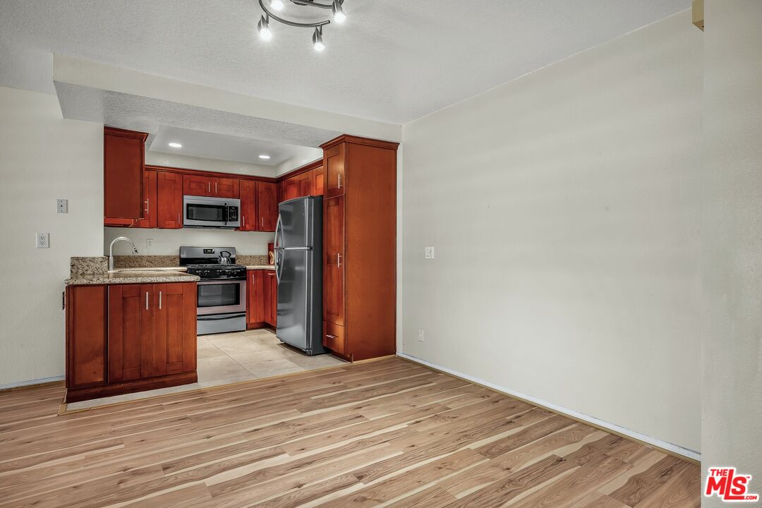8512 Tuscany Avenue, Unit 207 Playa del Rey, CA 90293 - Photo 7 of 45 a kitchen with stainless steel appliances granite countertop a refrigerator and a stove top oven
