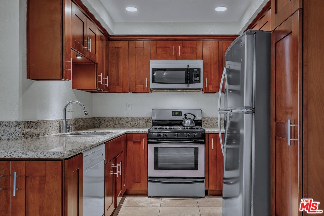 8512 Tuscany Avenue, Unit 207 Playa del Rey, CA 90293 - Photo 8 of 45 a kitchen with stainless steel appliances granite countertop a stove a sink and a microwave