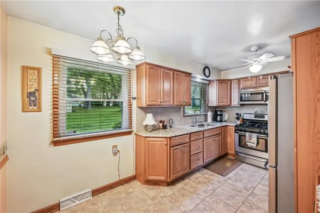 a kitchen with stainless steel appliances granite countertop a stove top oven a sink dishwasher and a refrigerator