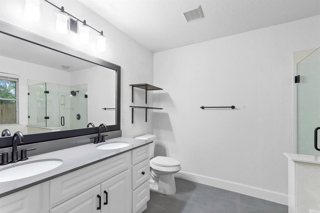 617 Barbara Way Bastrop, TX 78602 - Photo 9 of 20 A well-appointed bathroom features a double vanity, glass-enclosed shower, and sleek tile flooring.