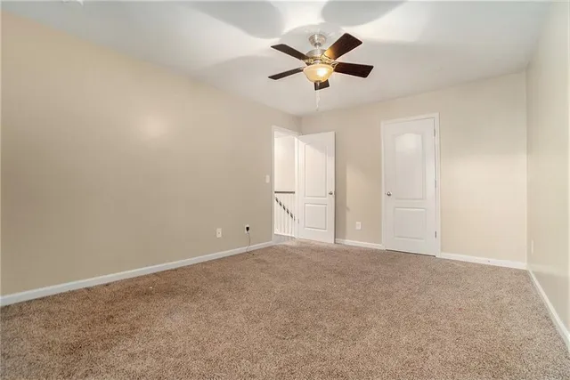 an empty room with chandelier fan and windows