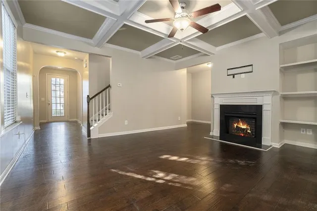 a view of a livingroom with a fireplace a ceiling fan and wooden floor