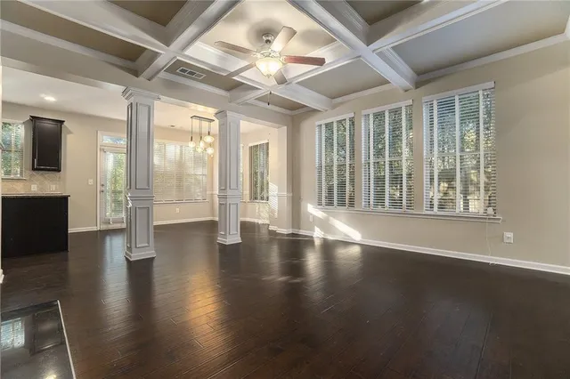 an empty room with wooden floor and large windows