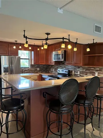 a kitchen with stainless steel appliances granite countertop a table chairs sink and cabinets