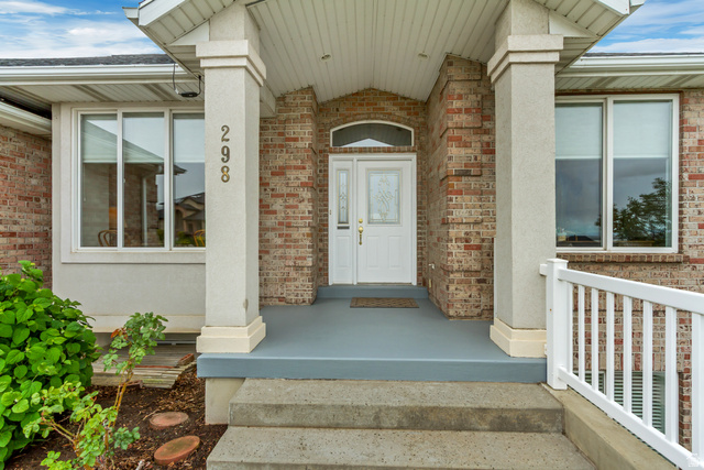 298 North Canyon Road Bountiful, UT 84010 - Photo 5 of 57 Brick exterior featuring a covered porch, white entry door with decorative glass, two large windows, concrete steps, and a white railing