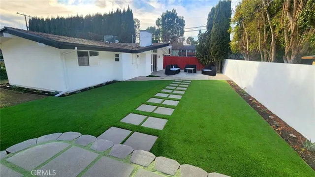 a view of a white house with a yard table and chairs