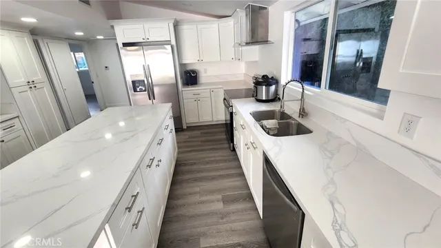 a kitchen with stainless steel appliances a refrigerator a sink a stove and white cabinets