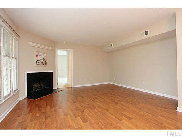 2821 Edridge Court, Unit 101 Raleigh, NC 27612 - Photo 5 of 25 a view of empty room with wooden floor and fireplace