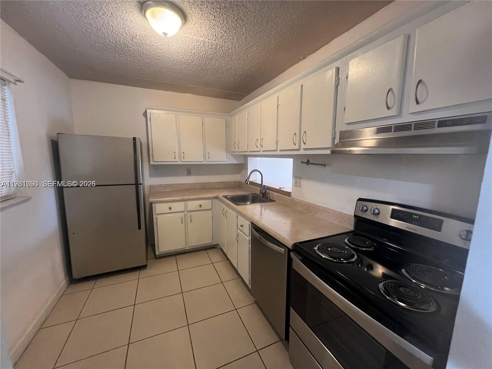 8500 Southwest 133rd Avenue Road, Unit 305 Miami, FL 33183 - Photo 3 of 7 a kitchen with a stove top oven and white cabinets