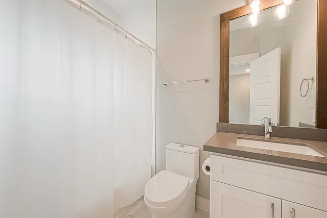 a bathroom with a granite countertop toilet sink mirror and vanity