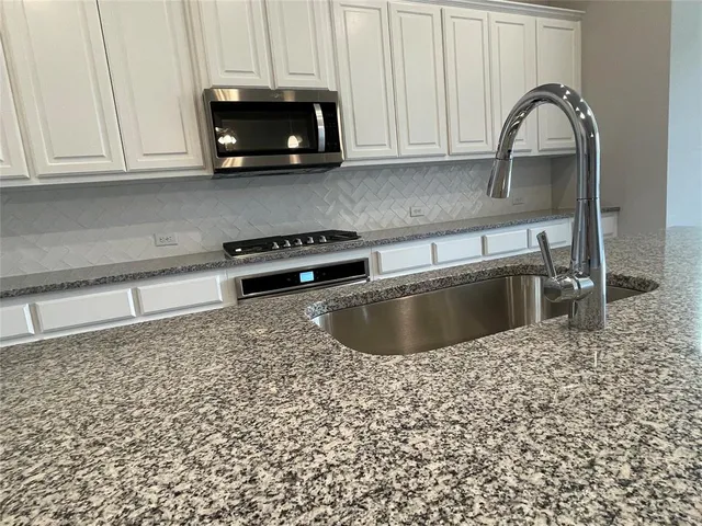 a kitchen with granite countertop a sink a stove and microwave