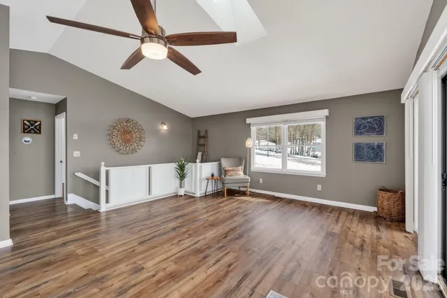 an empty room with wooden floor fan and windows