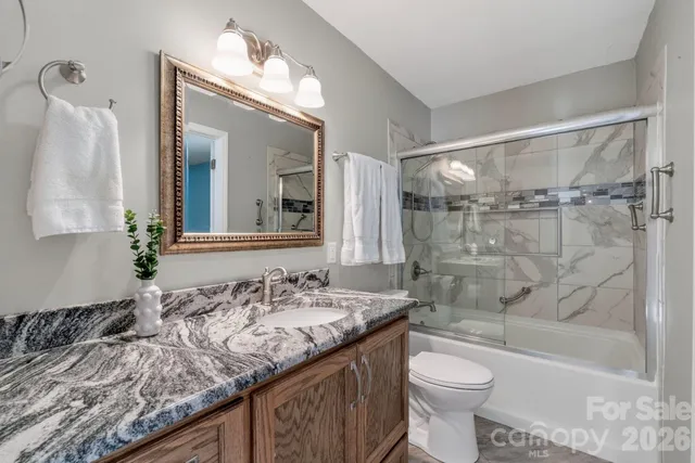 an empty room with wooden floor chandelier fan and windows