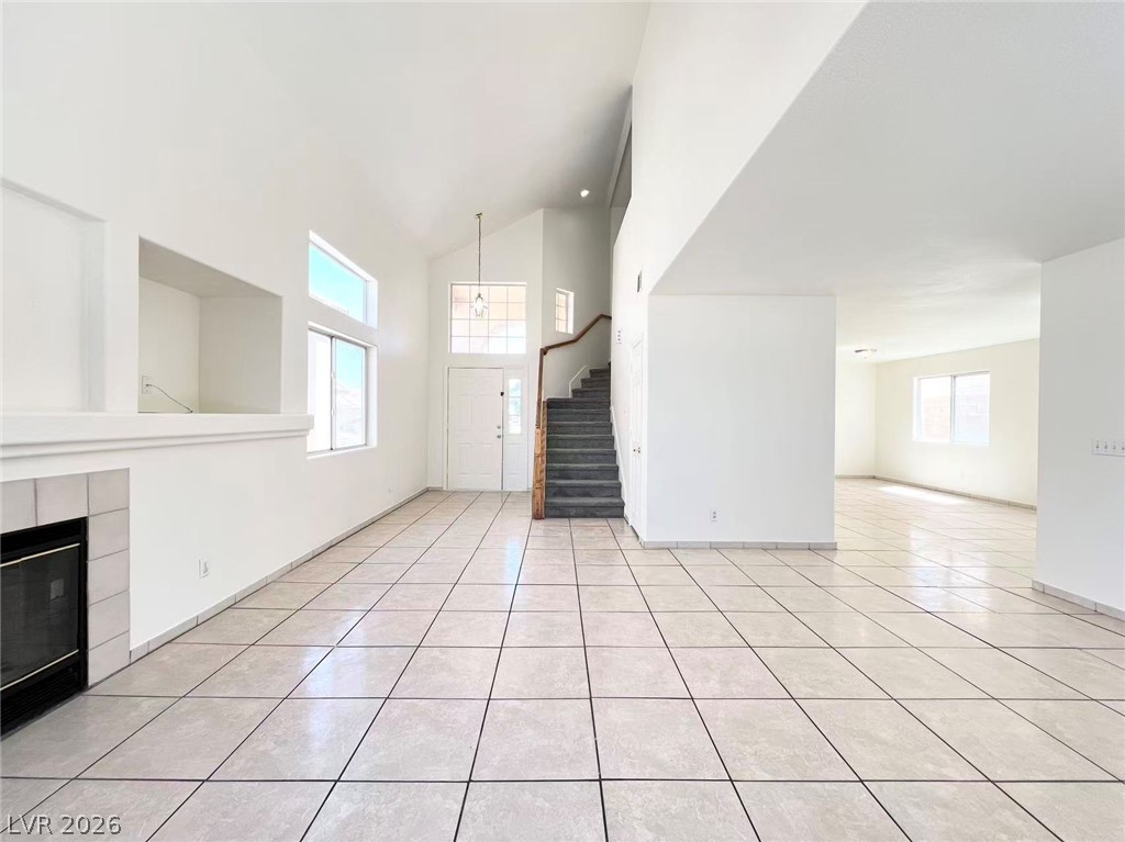 8284 West Rochelle Avenue Las Vegas, NV 89147 - Photo 3 of 29 Vast, well-lit interior showcasing soaring ceilings, a central staircase, and a corner fireplace.