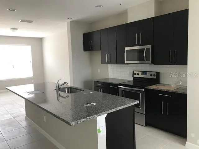 a kitchen with a sink a stove top oven and wooden cabinets