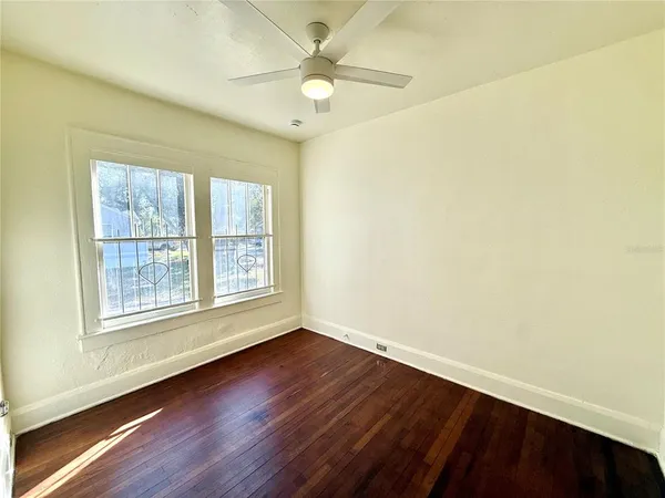 an empty room with wooden floor and windows
