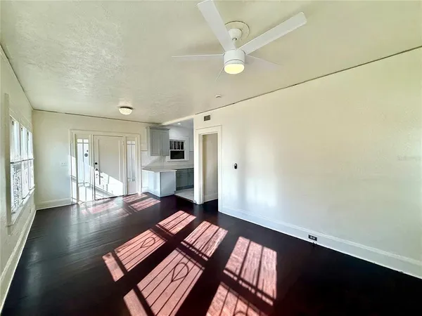 a view of an empty room with wooden floor and a window