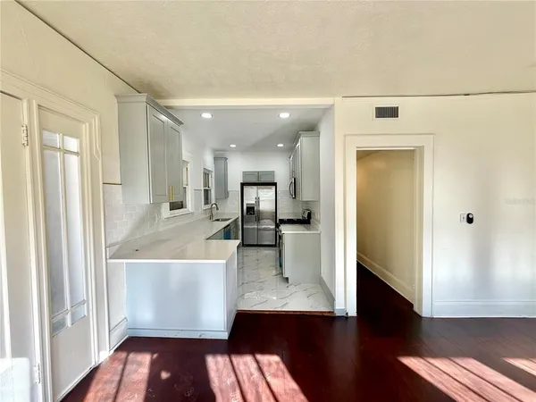 a view of a hallway with wooden floor windows and a kitchen