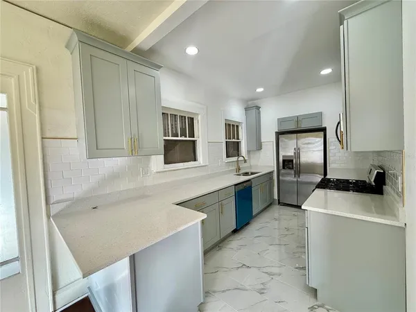 a kitchen with a sink a counter top space stainless steel appliances cabinets and a window