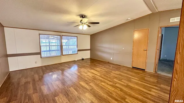 a view of an empty room with a window and wooden floor