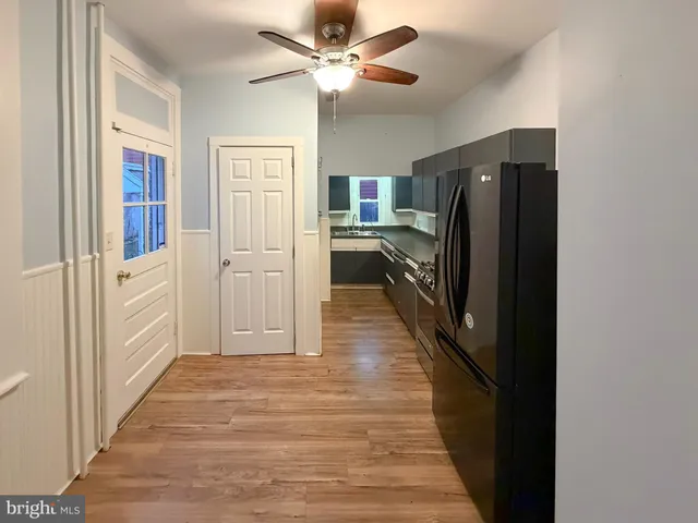 a hallway with wooden floor a ceiling fan and windows
