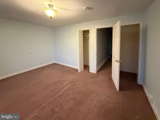 an empty room with closet and a ceiling fan