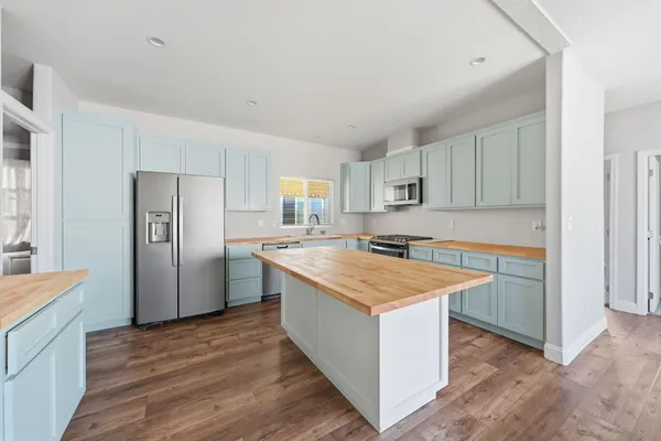 a kitchen with a stove a refrigerator a sink and dishwasher with wooden floor