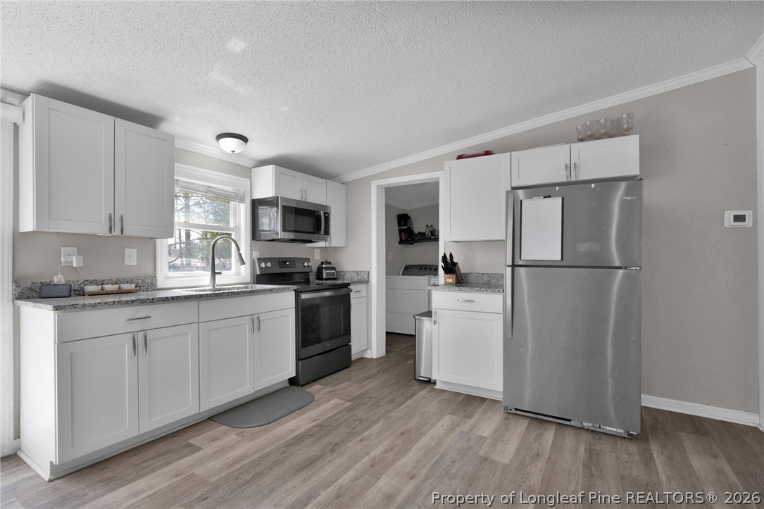 518 Inverary Drive Raeford, NC 28376 - Photo 12 of 30 a kitchen with a refrigerator stove and white cabinets