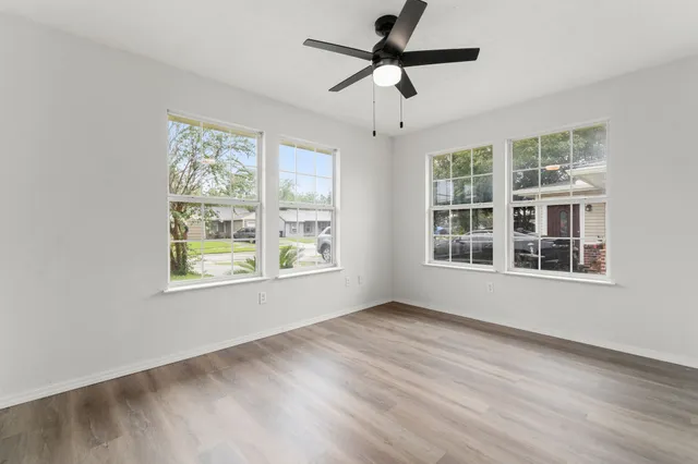 a view of an empty room with a window and wooden floor