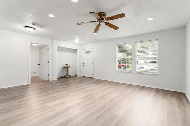 a view of an empty room with a window and wooden floor