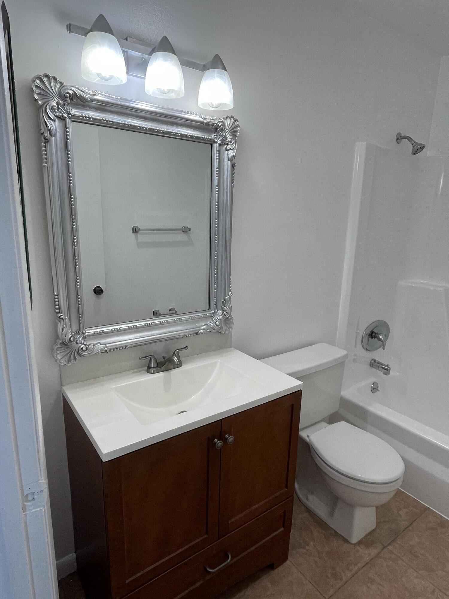 431 Jupiter Lakes Boulevard, Unit 2104C Jupiter, FL 33458 - Photo 12 of 28 a bathroom with a sink vanity mirror and toilet