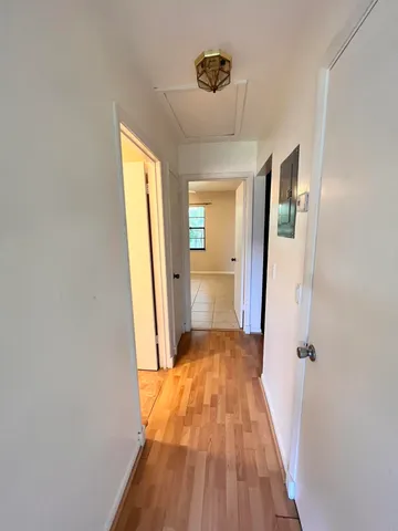 a view of a hallway with wooden floor and a bathroom