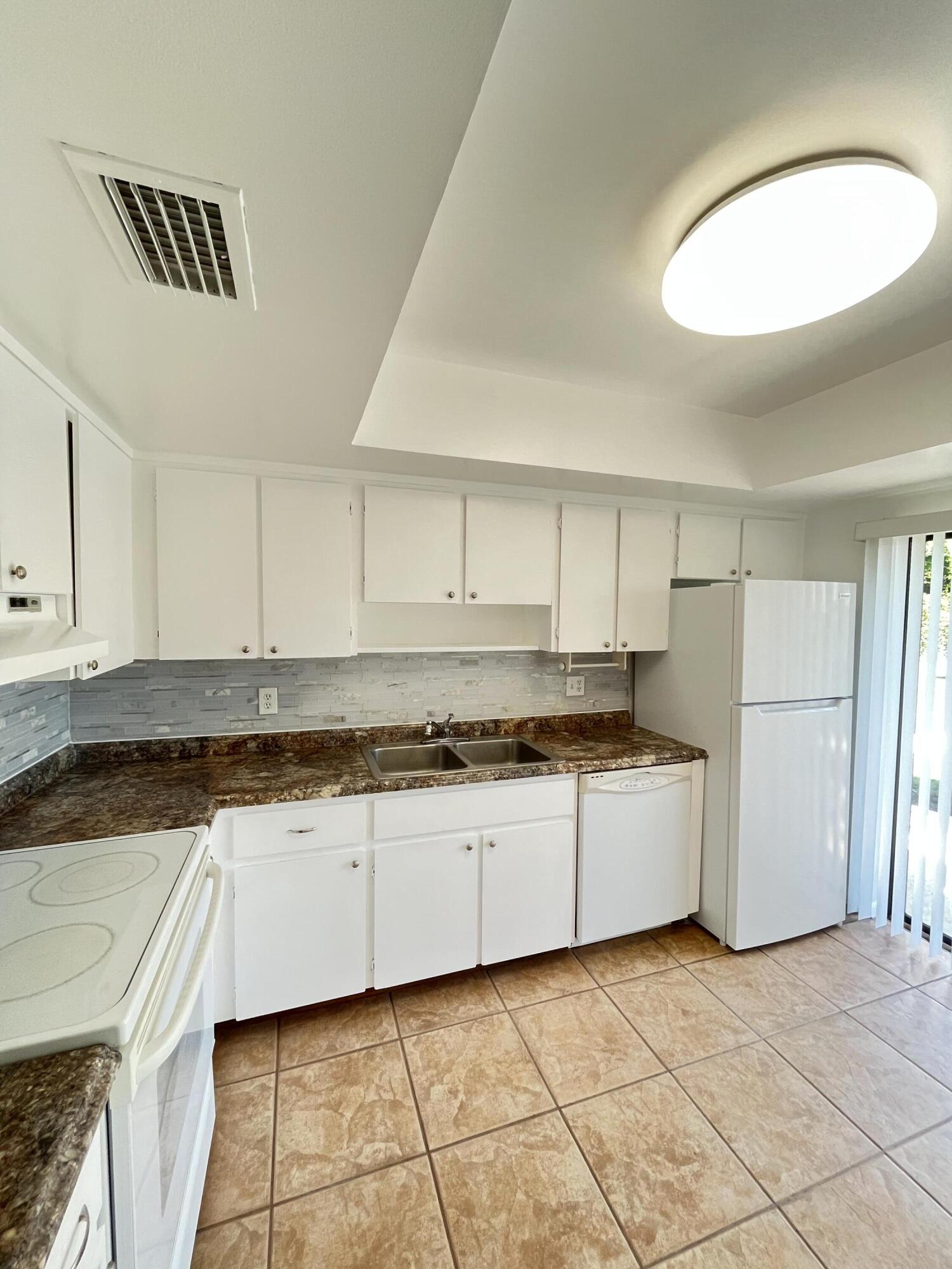 431 Jupiter Lakes Boulevard, Unit 2104C Jupiter, FL 33458 - Photo 6 of 28 a kitchen with granite countertop a stove a sink and a refrigerator