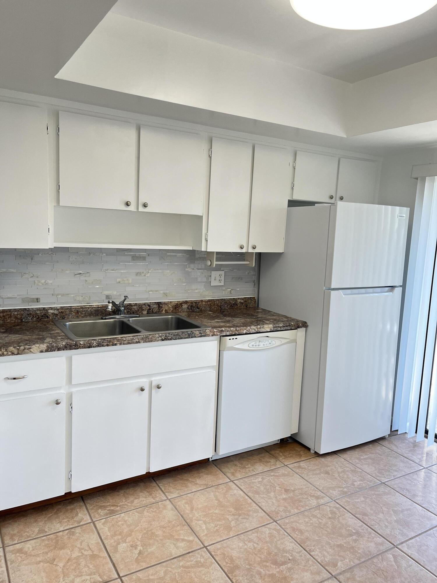 431 Jupiter Lakes Boulevard, Unit 2104C Jupiter, FL 33458 - Photo 7 of 28 a kitchen with granite countertop cabinets and white appliances