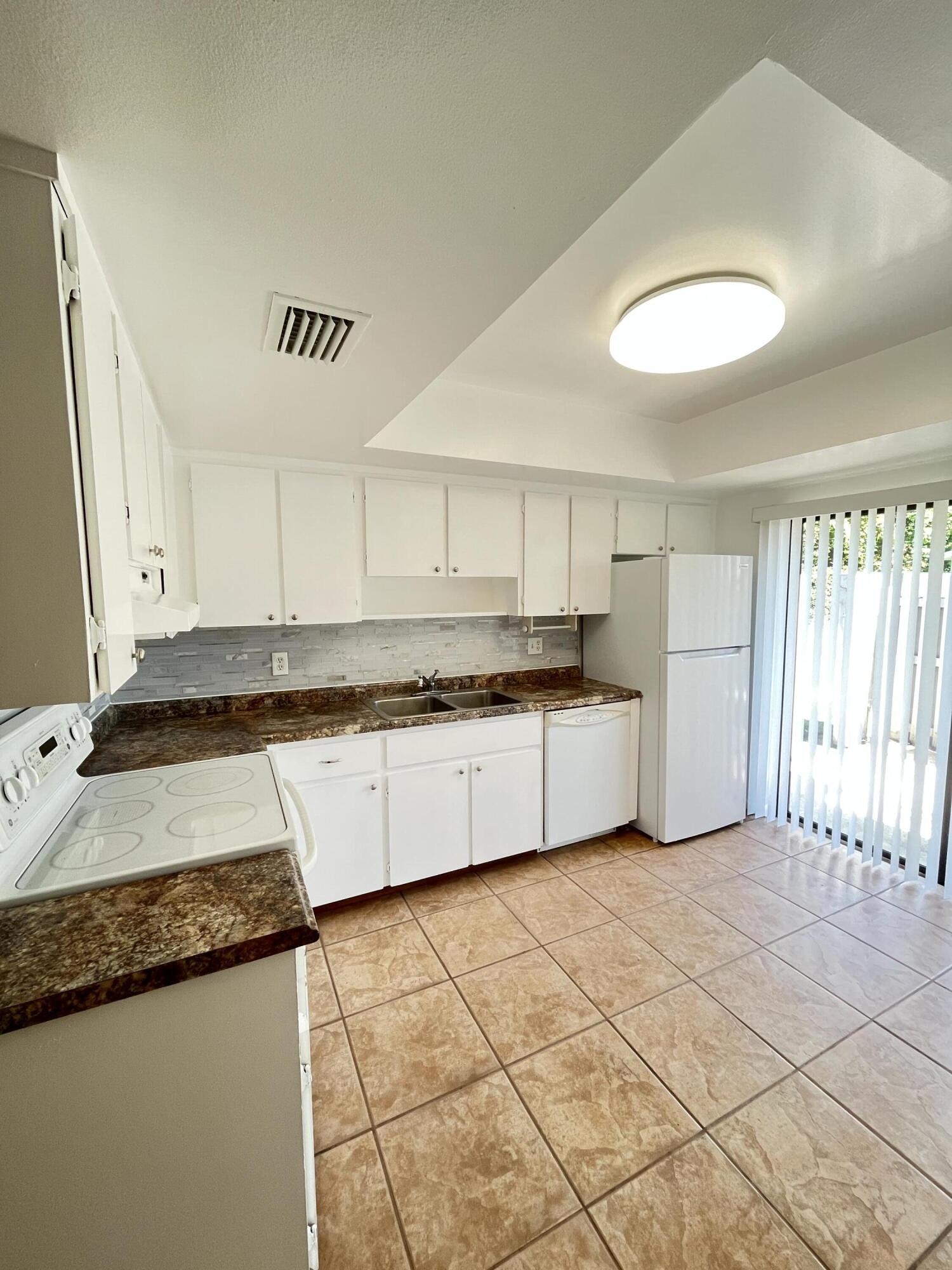 431 Jupiter Lakes Boulevard, Unit 2104C Jupiter, FL 33458 - Photo 8 of 28 a kitchen with a sink and a stove top oven