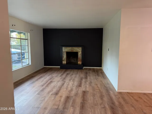 a view of empty room with wooden floor and fireplace