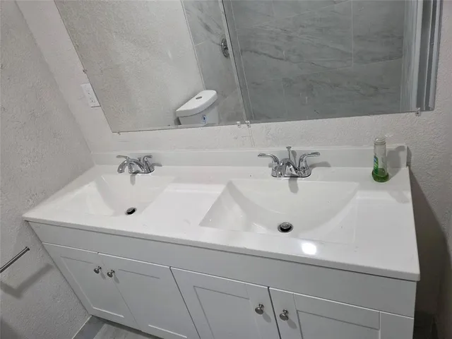 a bathroom with a sink a toilet and a mirror