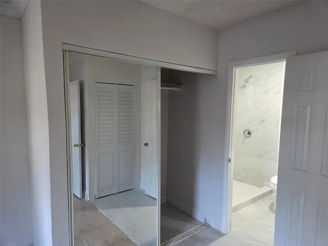 an empty room with chandelier fan and windows