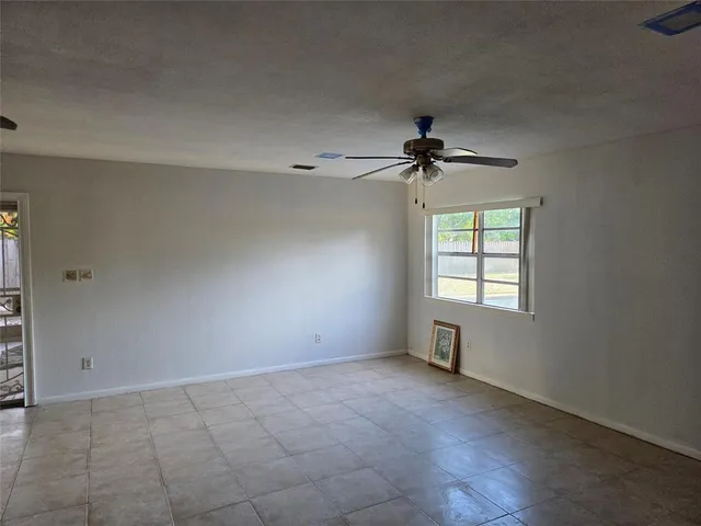 an empty room with windows and fan